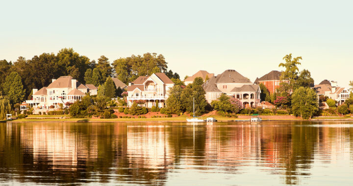 A row of luxury homes reflected in a lake.