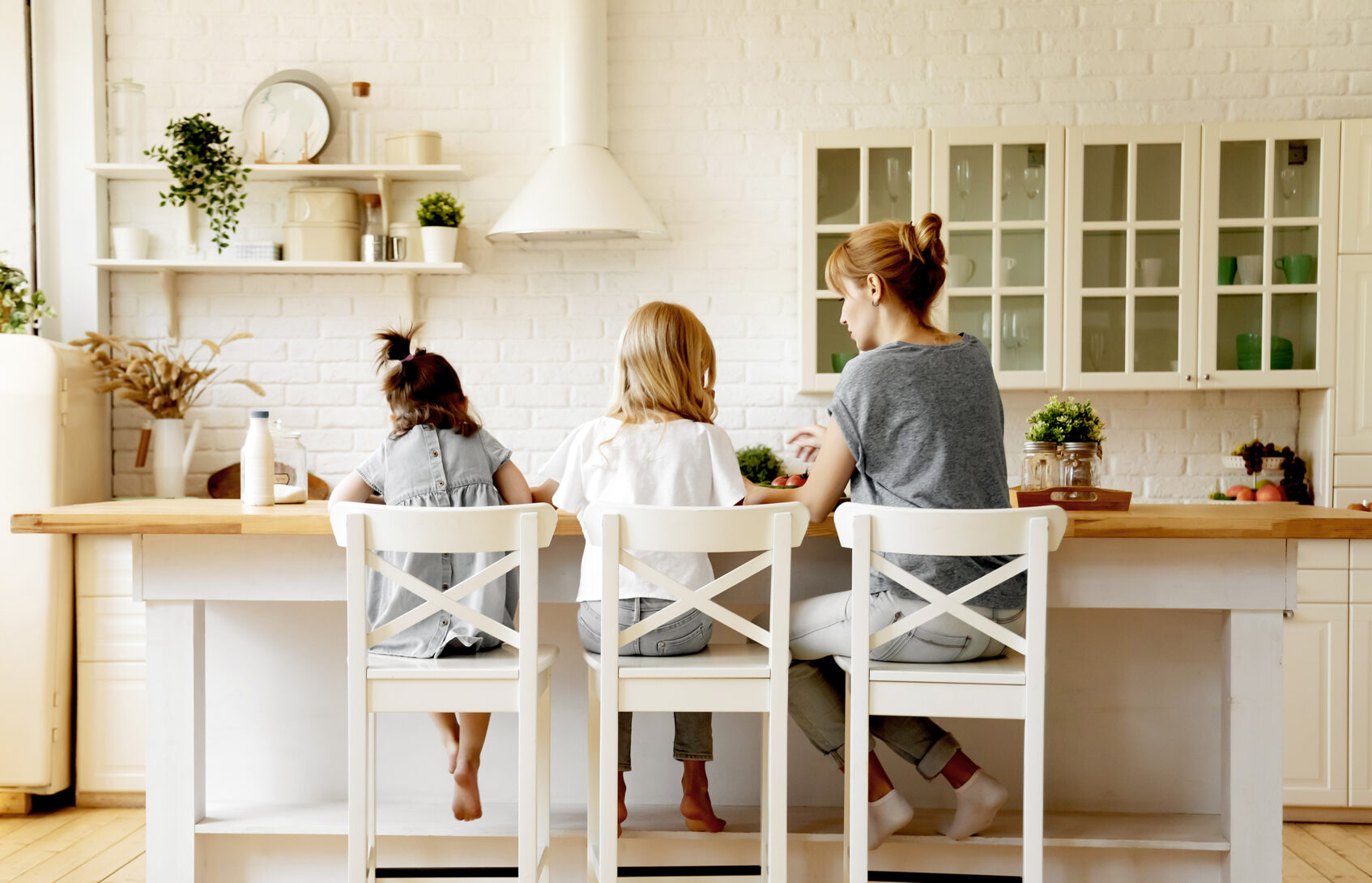 A mom and her two young daughters sitting in chairs at a table