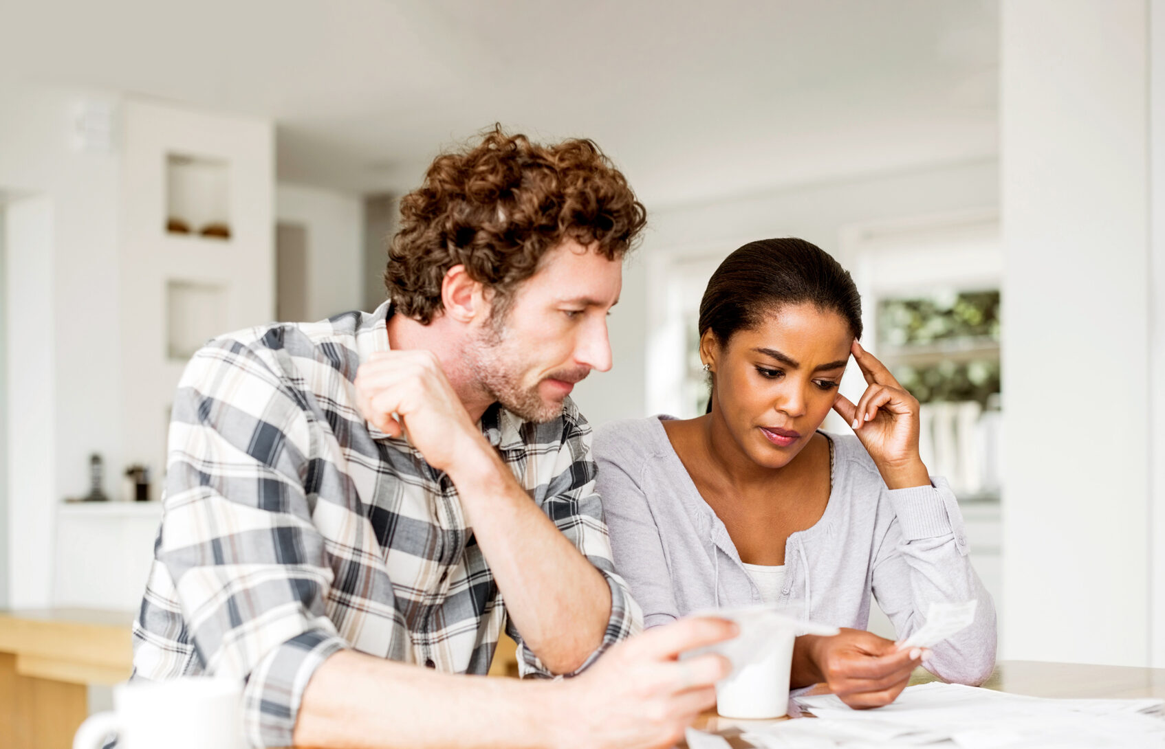 A couple sitting at the kitchen table looking at a receipt