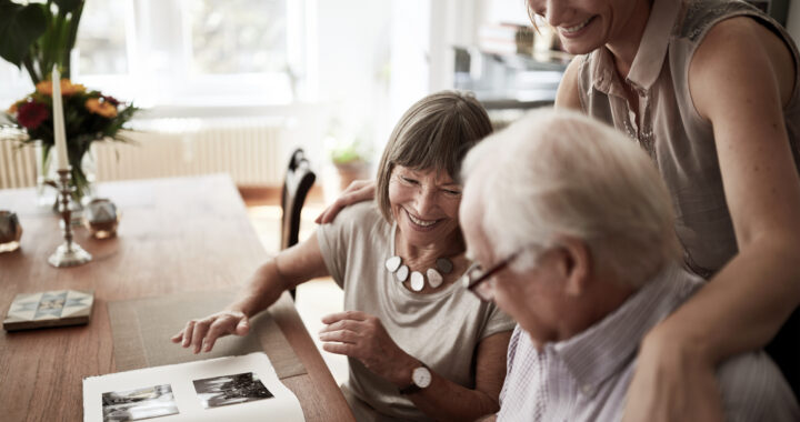 A family of three looking at a photo album on a desk.