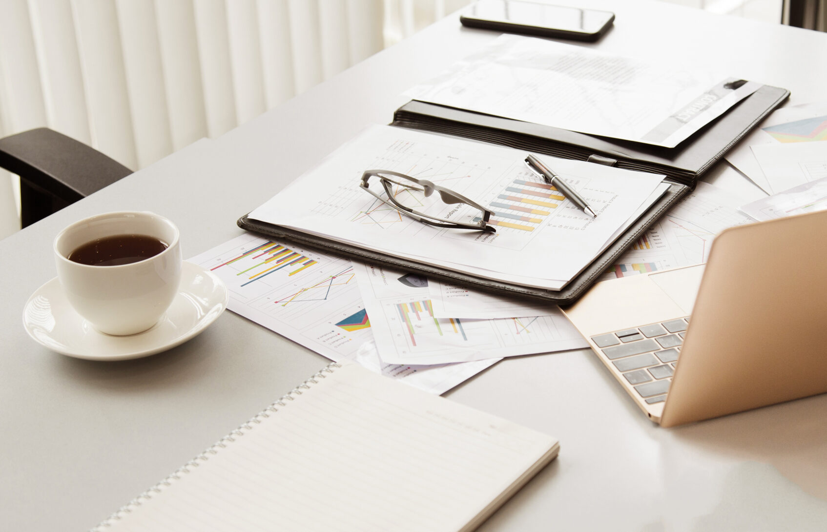 Coffee cup, notebook, and laptop on a desk
