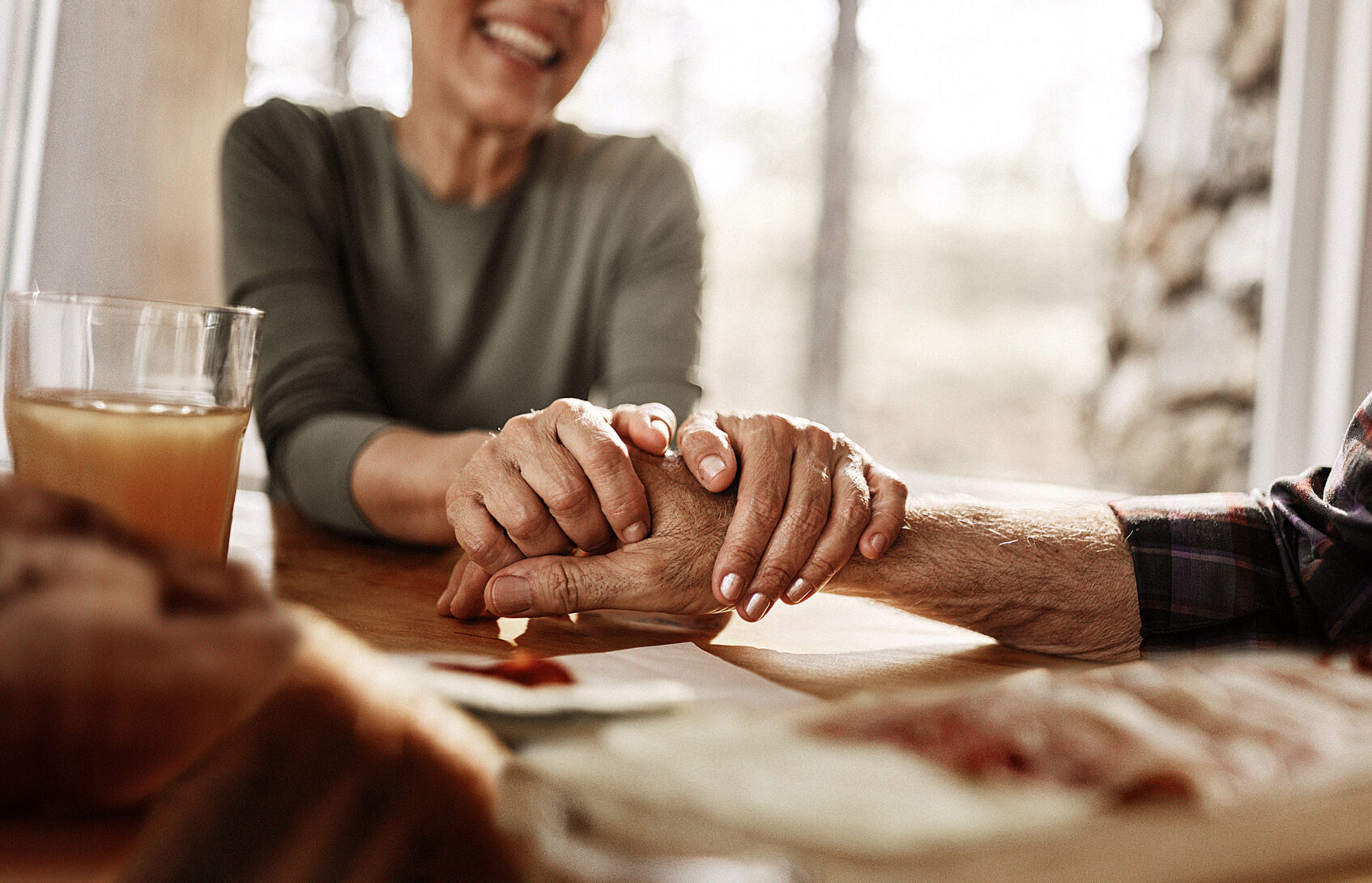 Woman seated at a table holding a man’s hand.