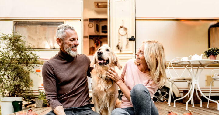 A man and woman sitting together on a deck with their dog