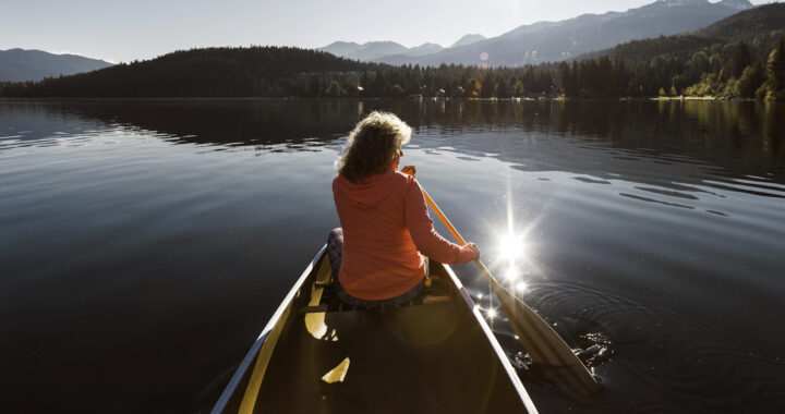 Woman paddling a canoe on a lake.
