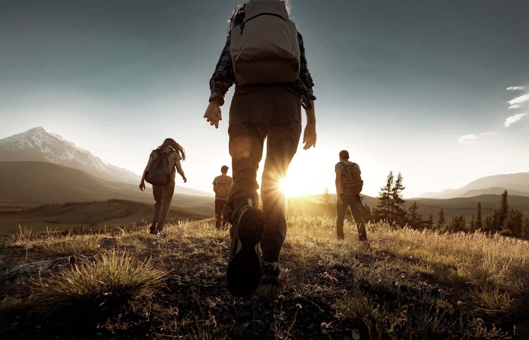Group of sporty people walks in mountains at sunset