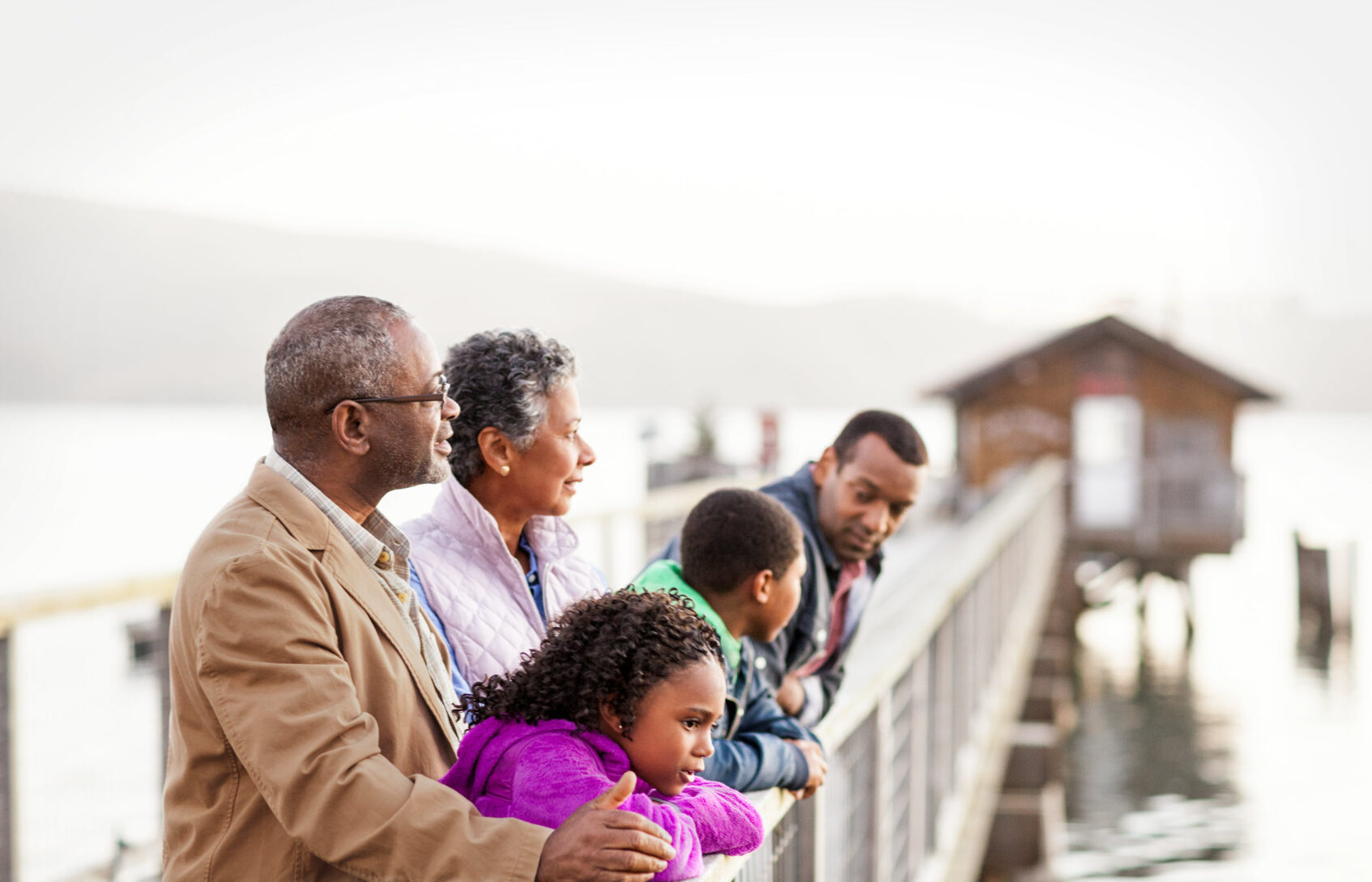 Three generations of family members gathered on a seaside pier.