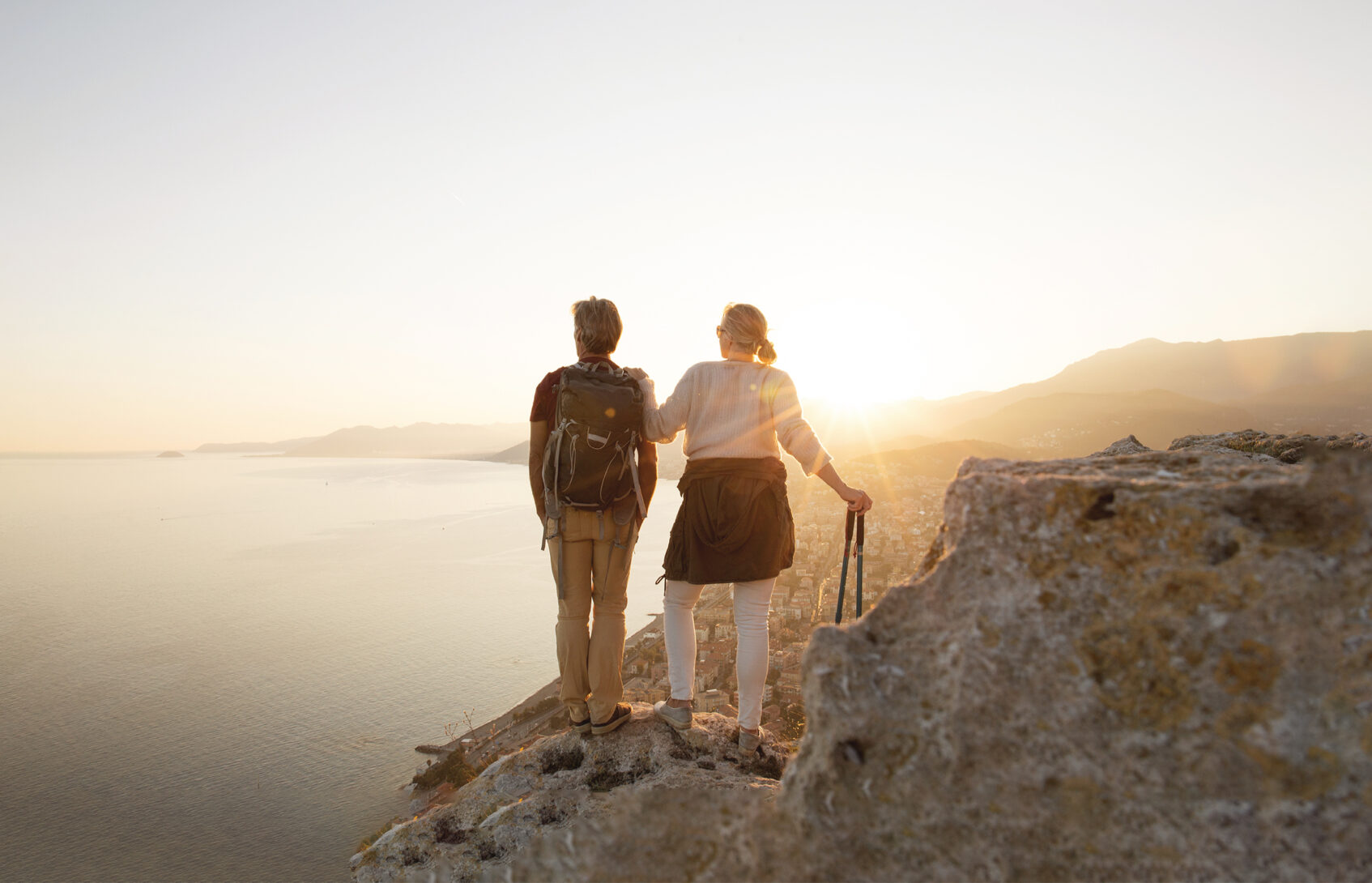 A hiking couple pauses to enjoy a view of the water.