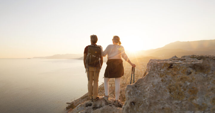 A hiking couple pauses to enjoy a view of the water.