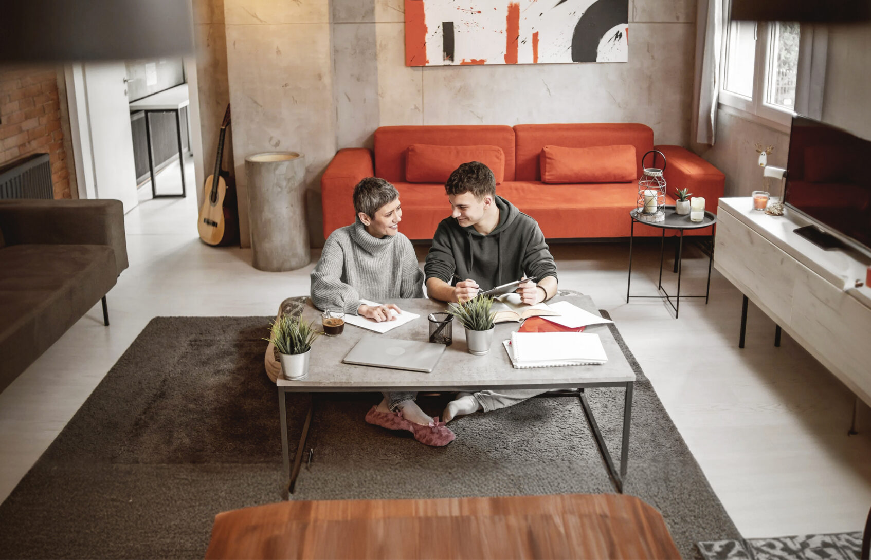 A mother and son review finances while sitting on the floor of their living room